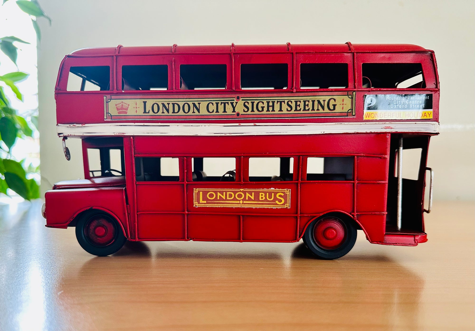 Model of a red double-decker bus with 'London City Sightseeing' and 'London Bus' signs on a metal surface.
